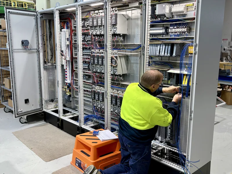 Technician wiring a lineup of industrial control cabinets