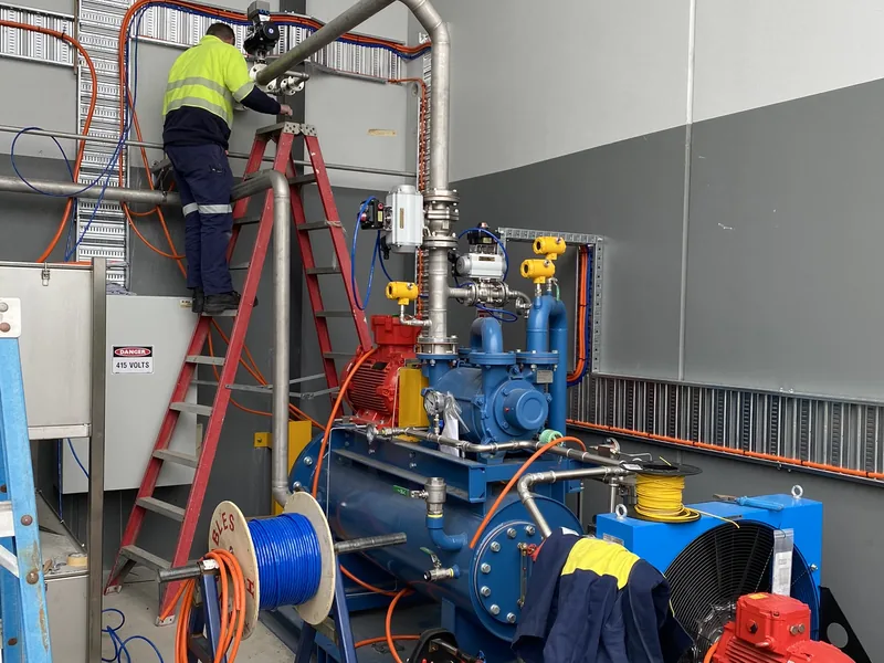 Electrician working at height on process pipework and pump installation
