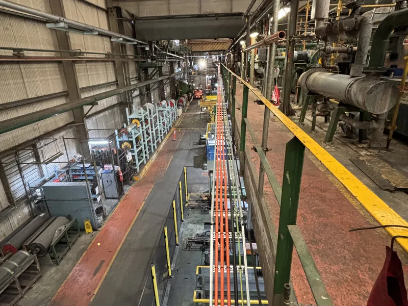 Heavy industrial plant interior with conveyor line and structural steel walkway