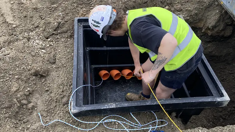 Electrician terminating underground conduits in a cable pit